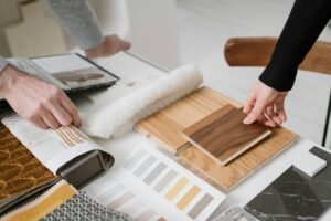 Hands selecting and comparing textile and wood samples for interior design.